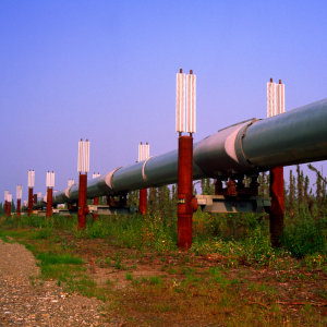 red and silver oil pipeline that is running through a field of dry fields